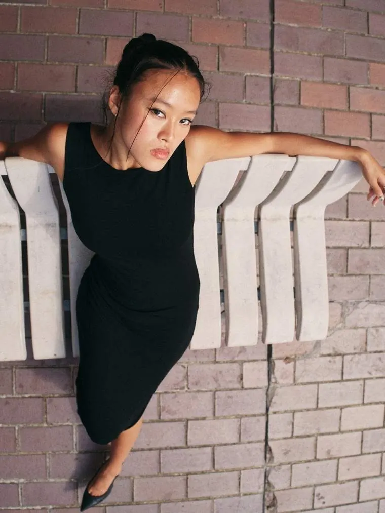 The Kallaus Dress worn against a brick wall
