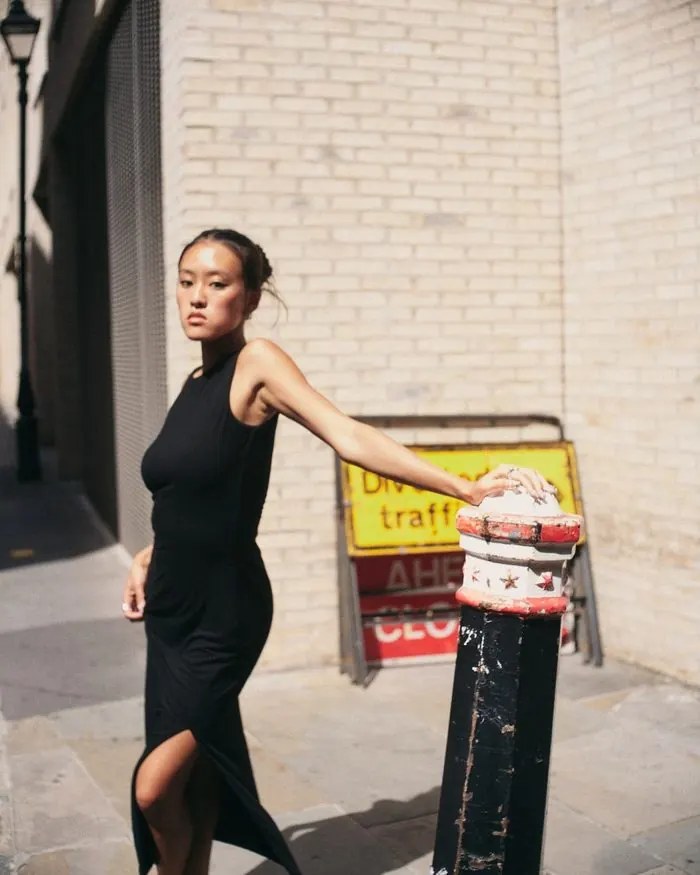 Leaning on a bollard at a street corner in hard midday sun.